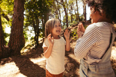 Fröhliche Mädchen spielen klatschende Spiele im Wald. Niedliche Kinder spielen Spiele in einem Park. - JLPSF19528