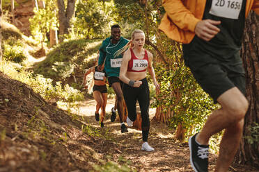 Eine Gruppe von Athleten läuft eine Strecke bergauf, Männer und Frauen laufen einen Marathon. - JLPSF19544