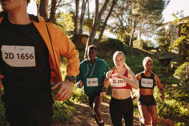 Eine multiethnische Gruppe von Athleten läuft auf einem Bergpfad. Ein Mann und eine Frau nehmen an einem Marathon-Meisterschaftsrennen teil. - JLPSF19554