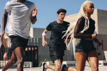 Fitte junge Leute, die gemeinsam in der Stadt laufen. Läufer, die am Morgen im Freien trainieren. - JLPSF19560