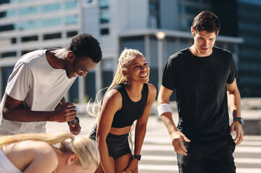 Multiethnische Freunde im Freien in der Stadt nach dem Training. Fitnessgruppe, die sich nach dem Training ausruht und lächelt. - JLPSF19569