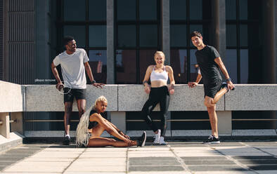 Fitnessgruppe, die sich nach dem Training ausruht. Multiethnische Gruppe von Läufern, die sich nach einer Trainingseinheit in der Stadt ausruht. - JLPSF19573