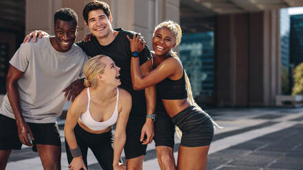 Group of men and women posing for a photograph after exercising outdoors. Multi-ethnic friends enjoying themselves after workout session. - JLPSF19588