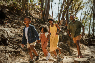 Junge Familie, die ihren Urlaub in einem Nationalpark genießt. Afrikanische Familie, die einen Bergpfad hinunterwandert und Spaß hat. - JLPSF19626