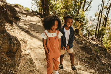 Cute boy and girl walking on a mountain trail. Boy and girl in casuals walking together on forest trail. - JLPSF19628