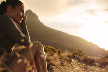 Woman sitting on meadow and looking away contemplating. Caucasian female tourist taking a rest after a country walk. - JLPSF19647