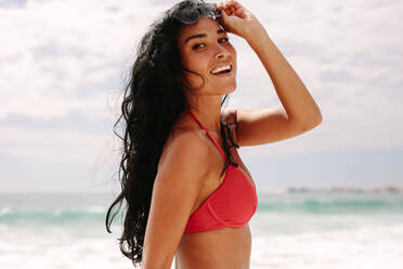 Pretty young woman in bikini walking along the beach. Female model strolling on the sea shore. - JLPSF19652