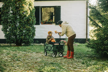 Vater spricht mit Sohn, der in einem Wagen vor dem Haus sitzt - VSNF00063