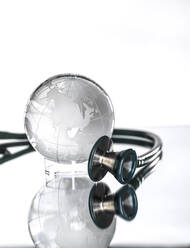 Studioaufnahme eines Stethoskops, das auf einen Glasglobus gerichtet ist - ABRF01002
