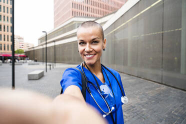Lächelnder älterer Angestellter im Gesundheitswesen, der ein Selfie auf dem Fußweg macht - OIPF02558
