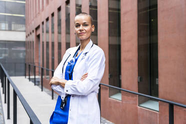 Confident mature nurse with arms crossed outside hospital - OIPF02574