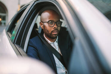 Afrikanischer Geschäftsmann, der mit dem Auto ins Büro fährt. Männlicher Glatzkopf, der sich beim Autofahren auf die Straße konzentriert. - JLPSF19778