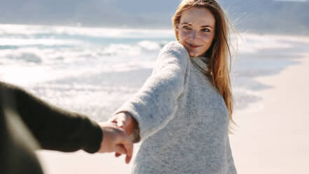 Woman enjoying walking with boyfriend along the seashore. Happy couple walking on the beach holding hands. - JLPSF19844