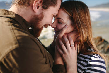 Close up of beard man with woman touching their foreheads at a beach. Romantic couple on the beach. - JLPSF19872