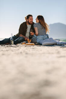 Schönes Paar genießt in einer guten Stimmung und Picknick-Tag am Strand. Low-Winkel Ansicht von Mann und Frau sitzen am Strand mit Essen und Getränken. - JLPSF19878