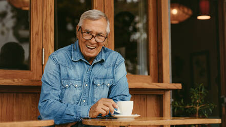 Porträt eines glücklichen Mannes im Ruhestand, der in einem Café Kaffee trinkt. Lächelnder älterer Mann, der sich im Café entspannt. - JLPSF19930