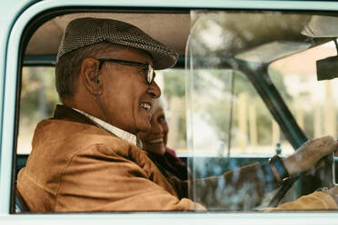 Happy senior wan driving a car with wife sitting on passenger seat. Senior couple out on a drive. - JLPSF19940