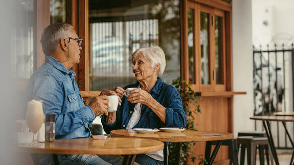 Älteres Ehepaar unterhält sich bei einer Tasse Kaffee im Café. Alter Mann und Frau sitzen im Café und unterhalten sich bei einem Kaffee. - JLPSF19971