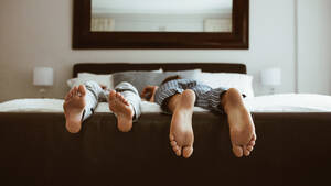 Füße von zwei Personen, die auf dem Bett schlafen. Personen, die in verschiedenen Positionen auf dem Bett schlafen. - JLPSF19980