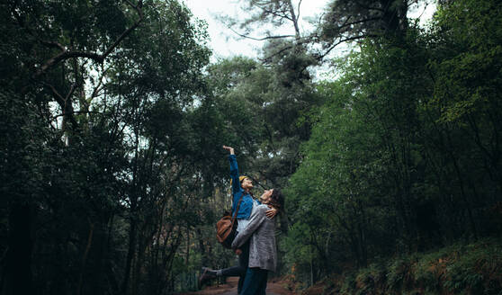 Beautiful rainforest with couple enjoying. Man carrying woman in arms with woman raising her hand and smiling. - JLPSF20039