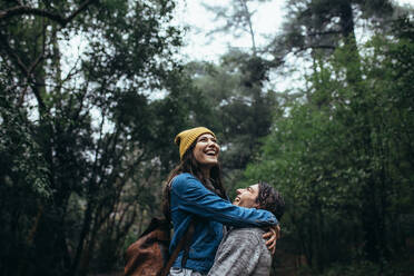 Young couple in a forest during rain having fun. Cheerful man and woman having great time together in rain. - JLPSF20043