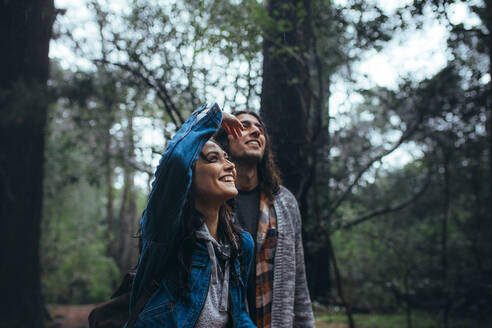 Paar, das durch den Wald spaziert und die Natur genießt. Junger Mann und Frau, die sich die Aussicht ansehen und im Wald lächeln. - JLPSF20051