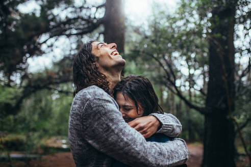 Couple in love embracing in the park under rain. Smiling young man hugging his girlfriend under the rain. - JLPSF20054