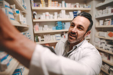 Professional pharmacist checking stock in an aisle of a local drugstore. Male chemist taking inventory at pharmacy store. - JLPSF20250