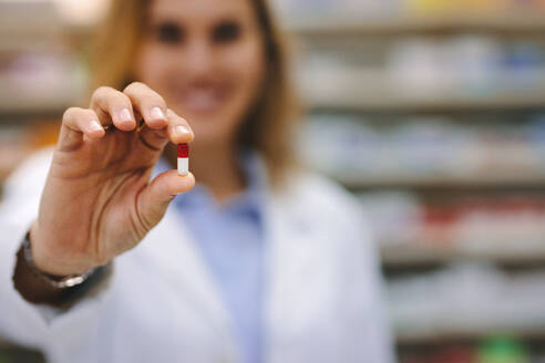 Hand of female pharmacist holding a medicine capsule. Close-up of hand holding a medical pill. Health care and prevention concept. - JLPSF20265