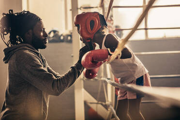 Boxtrainer, der einem jungen Boxer vor einem Kampf einen Kopfschutz umbindet. Ein junger Boxer spricht mit seinem Trainer während eines Boxkampfes. - JLPSF20329