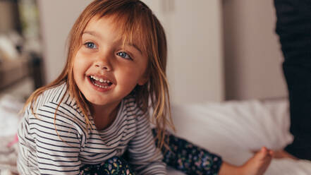 Close up of little girl sitting on bed playing with her father. Happy girl playing on bed at home. - JLPSF20356