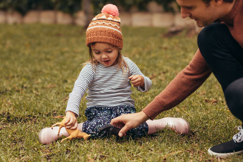 Vater und Tochter sitzen im Park und spielen mit Spielzeug. Vater und Tochter verbringen Zeit zusammen in einem Park. - JLPSF20389