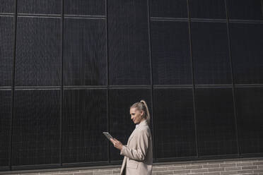 Smiling businesswoman using tablet PC by solar panels - UUF27683