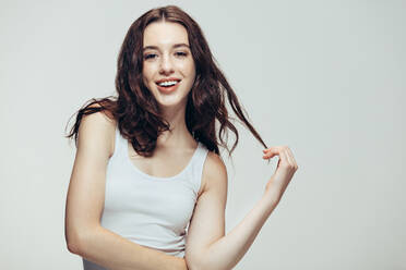 Portrait of attractive young woman in casuals standing against grey background. Caucasian female model looking at camera and smiling. - JLPSF20412