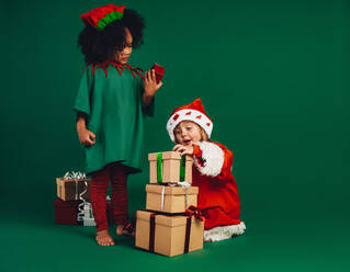 Glückliche Kinder spielen mit Weihnachtsgeschenk-Boxen sitzen auf dem Boden. Multi ethnische Kinder in Weihnachts-Kostüme Blick auf Geschenk-Boxen. - JLPSF20468