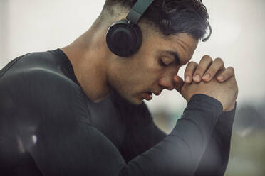 Junger Mann in Sportkleidung mit Kopfhörern macht eine Pause. Junger Mann fühlt sich müde nach intensivem Training. - JLPSF20527