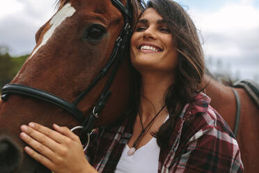 Nahaufnahme einer glücklichen jungen Frau, die ihr Pferd umarmt. Cowgirl, das ihr Pferd im Freien liebt. - JLPSF20555
