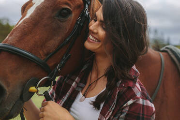 Nahaufnahme einer glücklichen Reiterin mit einem braunen Pferd. Lächelndes Cowgirl mit ihrem Pferd im Freien. - JLPSF20556