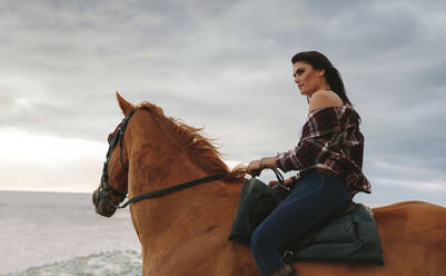 Junge Frau reitet auf einem Pferd am Strand. Frau reitet am Abend am Meer entlang. - JLPSF20560