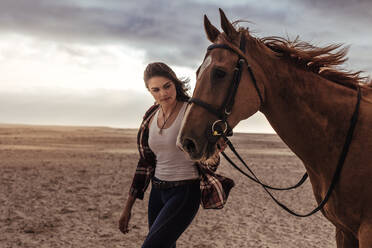 Junge Frau geht mit ihrem Pferd am Strand spazieren. Reiterin geht mit ihrem Hengst am Abend spazieren. - JLPSF20574