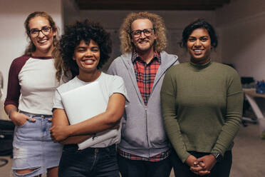 Porträt von jungen Leuten, die zusammen in einem Startup-Büro stehen, in die Kamera schauen und lächeln. Selbstbewusstes Team von IT-Profis. - JLPSF20628