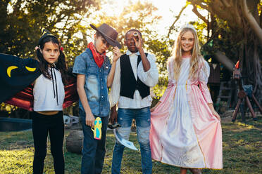 Eine Gruppe von Kindern steht im Garten und trägt verschiedene Kostüme. Junge Jungen und Mädchen haben Spaß im Freien mit Superhelden-Kostümen. - JLPSF20652