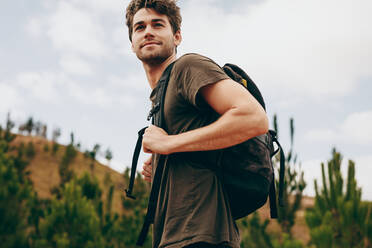 Mann beim Wandern auf dem Lande, Seitenansicht eines Mannes, der eine Tasche trägt und durch einen Wald läuft. - JLPSF20670