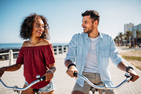 Ein Paar fährt mit dem Fahrrad auf der Straße und schaut sich an. Ein Touristenpaar, das Spaß daran hat, sich auf Fahrrädern durch die Stadt zu bewegen. - JLPSF20774