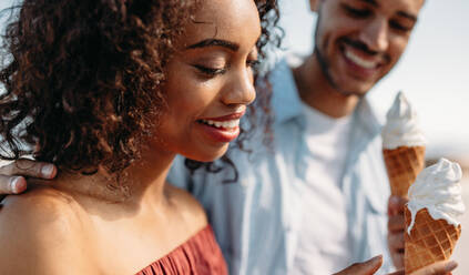 Smiling couple eating ice cream cone standing outdoors. Romantic couple enjoying ice cream. - JLPSF20776