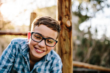 Close up of a smiling young boy outdoors. Happy teenage boy in eyeglasses playing outdoors. - JLPSF20807