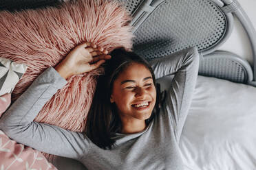 Junges Mädchen auf dem Bett liegend mit geschlossenen Augen und lachend. Mädchen in glücklicher Stimmung schlafend auf dem Bett. - JLPSF20836