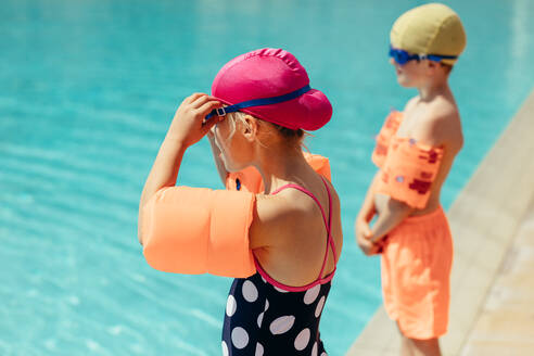 Kinder bereiten sich auf den Schwimmunterricht vor. Mädchen und Junge in Badekleidung stehen am Pool. - JLPSF20908