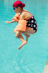 Girl jumping into the swimming pool. Child wearing swimming gear diving into the water. - JLPSF21100