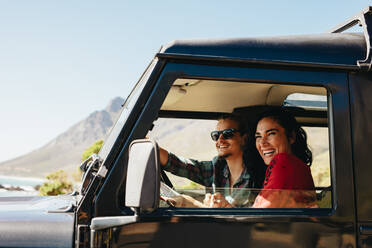 Glückliches junges Paar auf einer Autofahrt. Lächelnde junge Frau mit ihrem Freund am Steuer eines Autos. - JLPSF21153